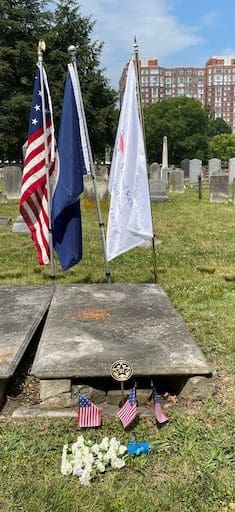 Grave of Dr. James Carson in Christ Church Cemetery, marked with American flags and ceremonial banners during a War of 1812 commemorative event.
