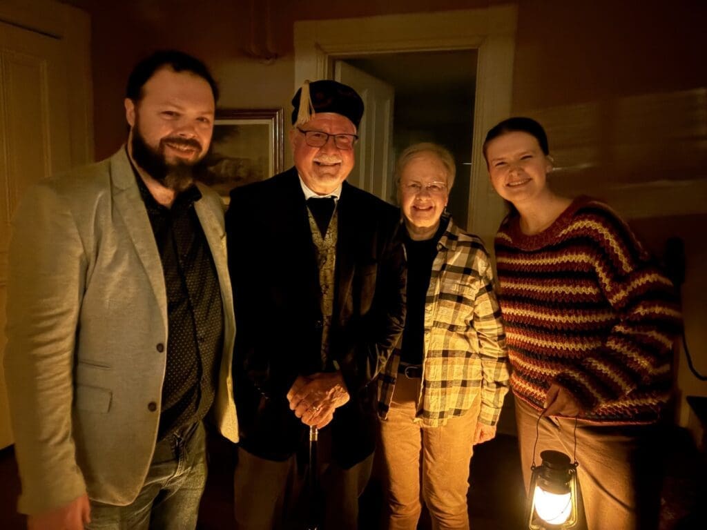 David Heiby portraying E. E. Downham during a February 2026 Lantern Tour at the Lee-Fendall House Museum in Alexandria, Virginia, with Benjamin Smith, Christine Heiby, and Museum Manager Jenny Waters.