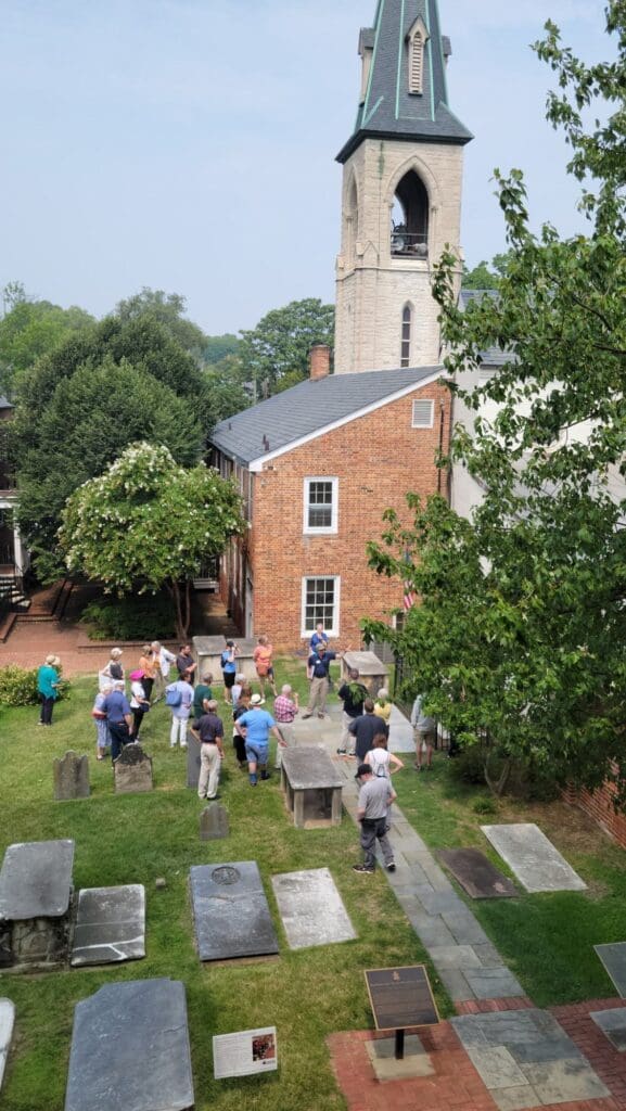 Guests gather around the Tomb of the Unknown Soldier at the Old Presbyterian Meeting House, with the Flounder House and Basilica of Saint Mary tower beyond.